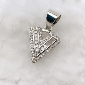 Macro detail of silver V-letter pendant with zircon stones on white plush background