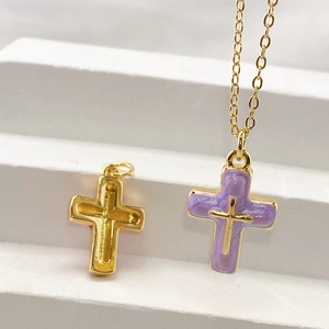 Detailed close-up of golden and purple marble cross pendants on a white stand