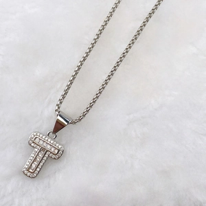 Detailed macro view of silver T-letter pendant with pave set zircons and baguette stones