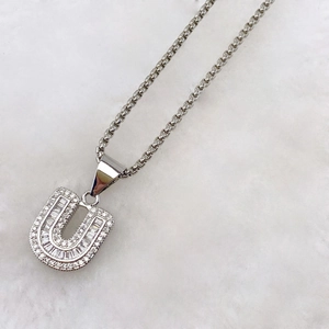 Detailed close-up of zircon-encrusted silver letter U pendant with round and baguette stones