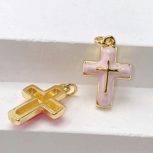 Macro view of gold cross charms with pink enamel inlay for DIY jewelry design