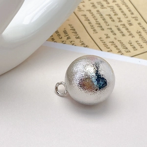 Macro shot of a silver hollow copper bead pendant with a brushed hammer texture for DIY jewelry