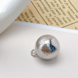 Close-up of a silver brushed hollow metal bead charm for DIY jewelry making