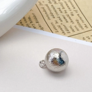 Macro detail of silver textured hollow bead pendant with unique hammered finish for DIY jewelry