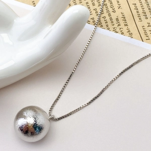 Detail of silver brushed hollow copper bead pendant on a classic box chain
