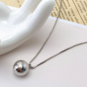 Macro view showing the textured surface of a hollow brushed silver bead pendant