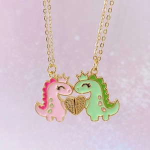 Detailansicht der rosa und grünen Dino-Anhänger mit Goldkronen und einem Herzanhänger