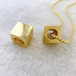 Polished gold square cube pendant necklace with elegant box chain on soft white fur