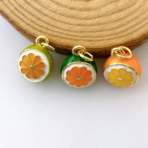 Three colorful enamel fruit pendants including orange and watermelon on wooden texture base