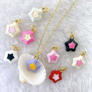 Detail of colorful enamel star charms and gold-plated necklace on white plush background