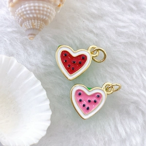 Detailed macro view of heart-shaped watermelon enamel charms with gold plating for DIY crafts