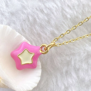 Detailed view of a pink heart-shaped star pendant with gold plating on a plush background