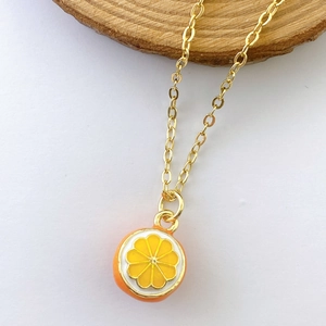 Detailed close-up of a gold-plated necklace with a creative enamel orange slice pendant