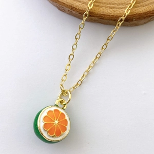 Detail of orange slice pendant with green enamel back on delicate gold necklace chain