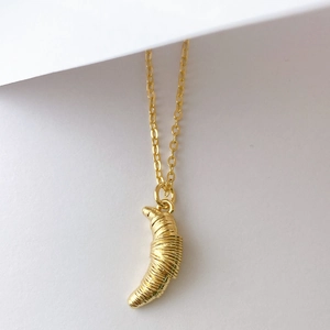 Détail macro du collier pendentif croissant 3D avec texture spirale dorée polie