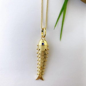 Detail of golden koi fish pendant featuring realistic scales and a blue gemstone eye