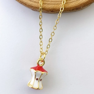 Close-up of creative apple core pendant with red enamel and gold plated details