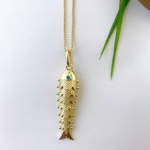 Macro shot of gold koi carp pendant featuring detailed scales and a blue gemstone eye