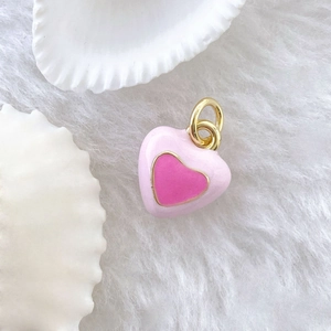 Pink heart pendant with gold accents on white fur and shell background