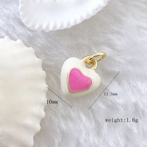 Macro view of a 10mm cream enamel heart pendant with a pink center and gold plating