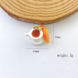 Macro detail of miniature coffee cup and croissant pendant with gold ring, 14mm size