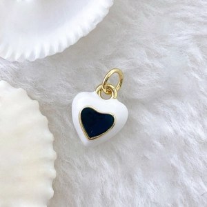 Detail of a white enamel heart pendant with golden edges on a soft white fur background