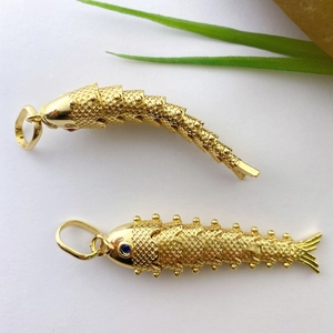 Close-up of flexible koi fish pendants in gold plating with blue sapphire-like eyes