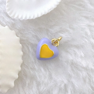 Close-up of heart charm with violet enamel, yellow center and golden metal ring
