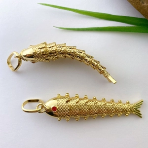Macro view of gold-plated koi fish pendants with detailed scale texture and red stone eyes