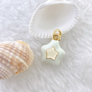Detail of mint green enamel star pendant with gold star inlay on soft white fur