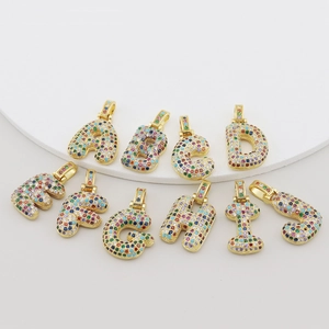 Macro detail of alphabet pendants A-J with colorful cubic zirconia in gold plating