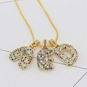 Close-up of golden alphabet pendants A, E, D set with vibrant multi-colored micro zircons