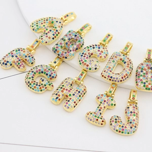 Close-up of gold-plated copper alphabet pendants with colorful cubic zirconia stones