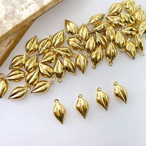 Detailed close-up of golden olive-shaped pendants with vertical ridges and top hanging loops