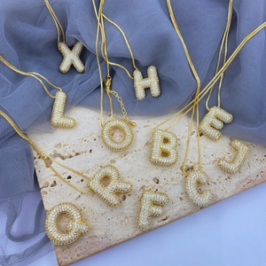 Detailed view of gold plated bubble letter pendants with sparkling zircon pavé on box chains
