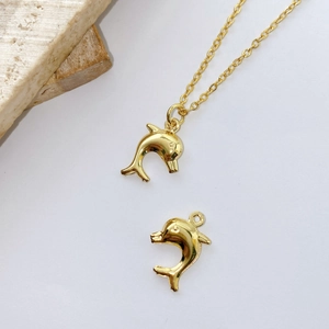 Macro view of polished gold dolphin charms and chain necklace on stone background