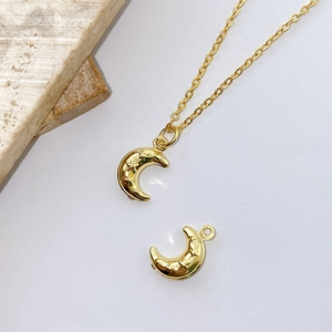 Macro shot of gold crescent moon pendants with star engravings on a minimalist background