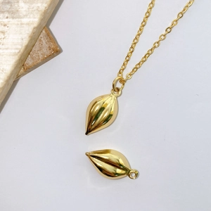 Macro shot of gold-plated leaf pendants and o-chain necklace on minimalist white background