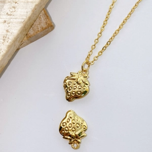 Detailed close-up of a gold-plated strawberry pendant with textured relief and fine chain