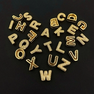 Macro shot of 26 gold alphabet letter beads with white zircon inlay for DIY jewelry
