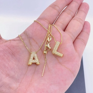 Detail of adjustable gold zircon letter necklaces with A and L pendants on hand