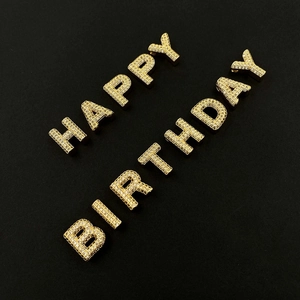 Macro view of gold plated 3D alphabet charms spelling HAPPY BIRTHDAY with pave zircon settings