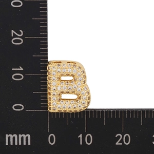 Macro shot of gold-plated letter B pendant with cubic zirconia inlay and mm ruler scale