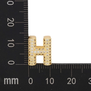 Macro detail of H letter gold pendant with cubic zirconia inlay measuring 12mm size
