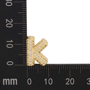 Detail showing the 12mm gold letter K pendant with cubic zirconia on a measuring scale