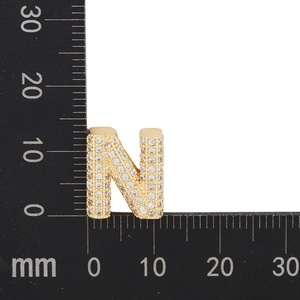 Macro shot of gold zircon letter N pendant with measurement scale for size reference
