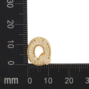 Detail view of 12mm gold plated letter Q pendant with cubic zirconia stones on scale