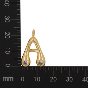 Detailed macro view showing a gold-plated letter A pendant with cubic zirconia on a scale