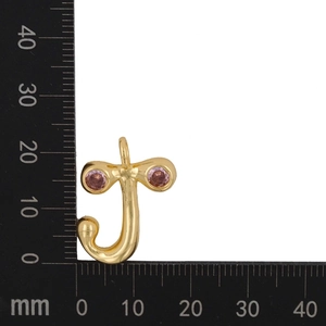 Detailed measurement of a gold letter J pendant with pink zircon stones on a scale