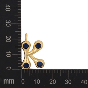 Macro size measurement of a gold letter K pendant with blue zircon stones, 18mm height